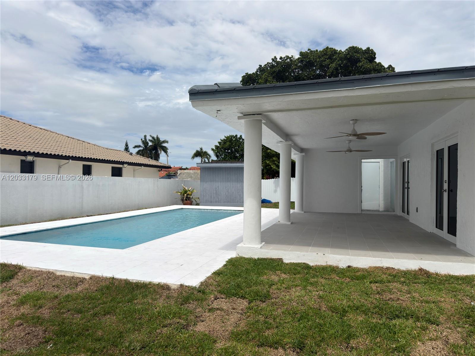 A backyard features a rectangular swimming pool, a covered patio with ceiling fans, and grass — 13895 SW 22nd St, Miami FL 33175, MIAMI, FL