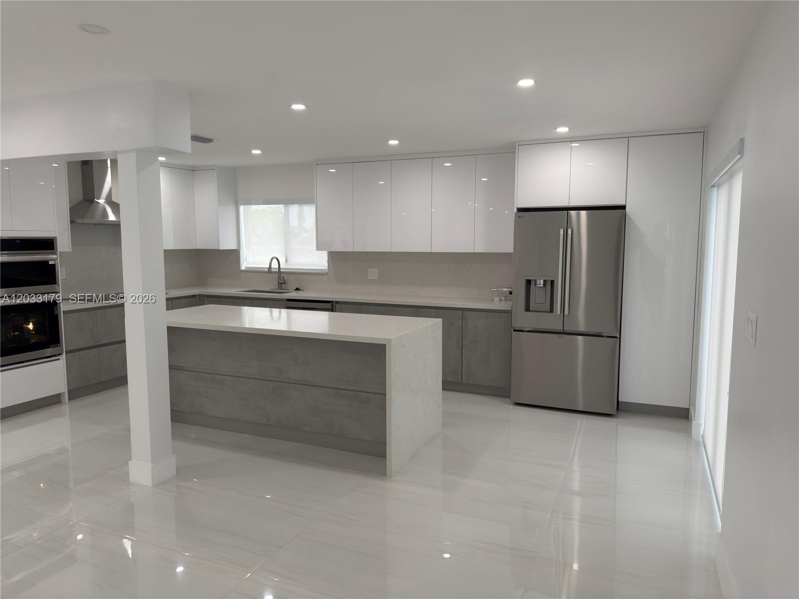 A modern kitchen features white upper cabinets, gray lower cabinets, and a white quartz island — 13895 SW 22nd St, Miami FL 33175, MIAMI, FL