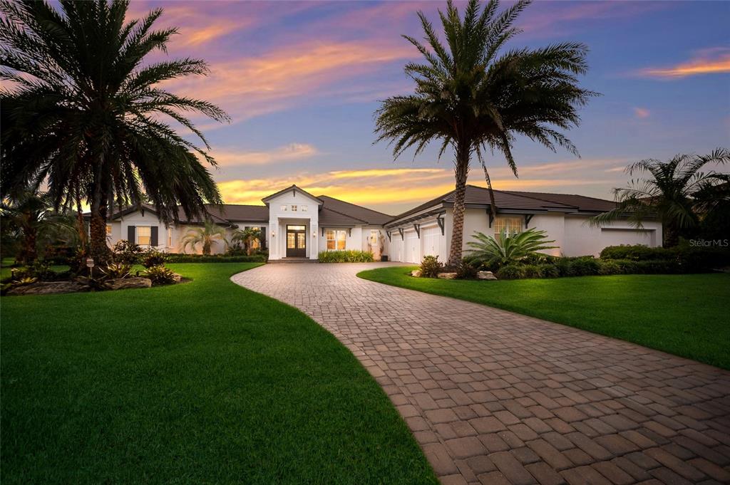 A single-story house with a paved driveway and palm trees under a sunset sky — 19433 NEWLANE PLACE, BRADENTON, FL