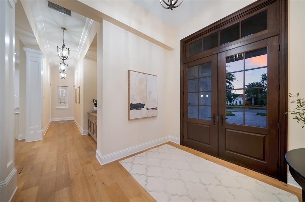 A bright entryway features hardwood floors, a patterned rug, and double dark wood glass doors — 19433 NEWLANE PLACE, BRADENTON, FL