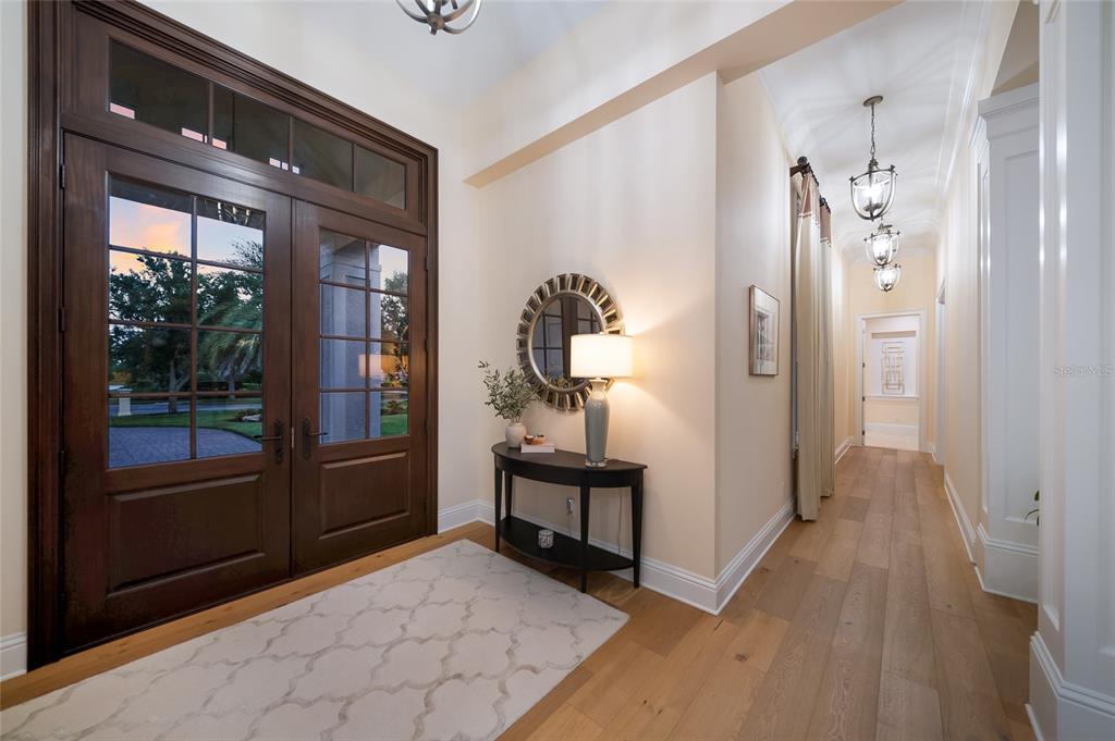 A foyer with a wooden double door, a console table, and a long hallway — 19433 NEWLANE PLACE, BRADENTON, FL