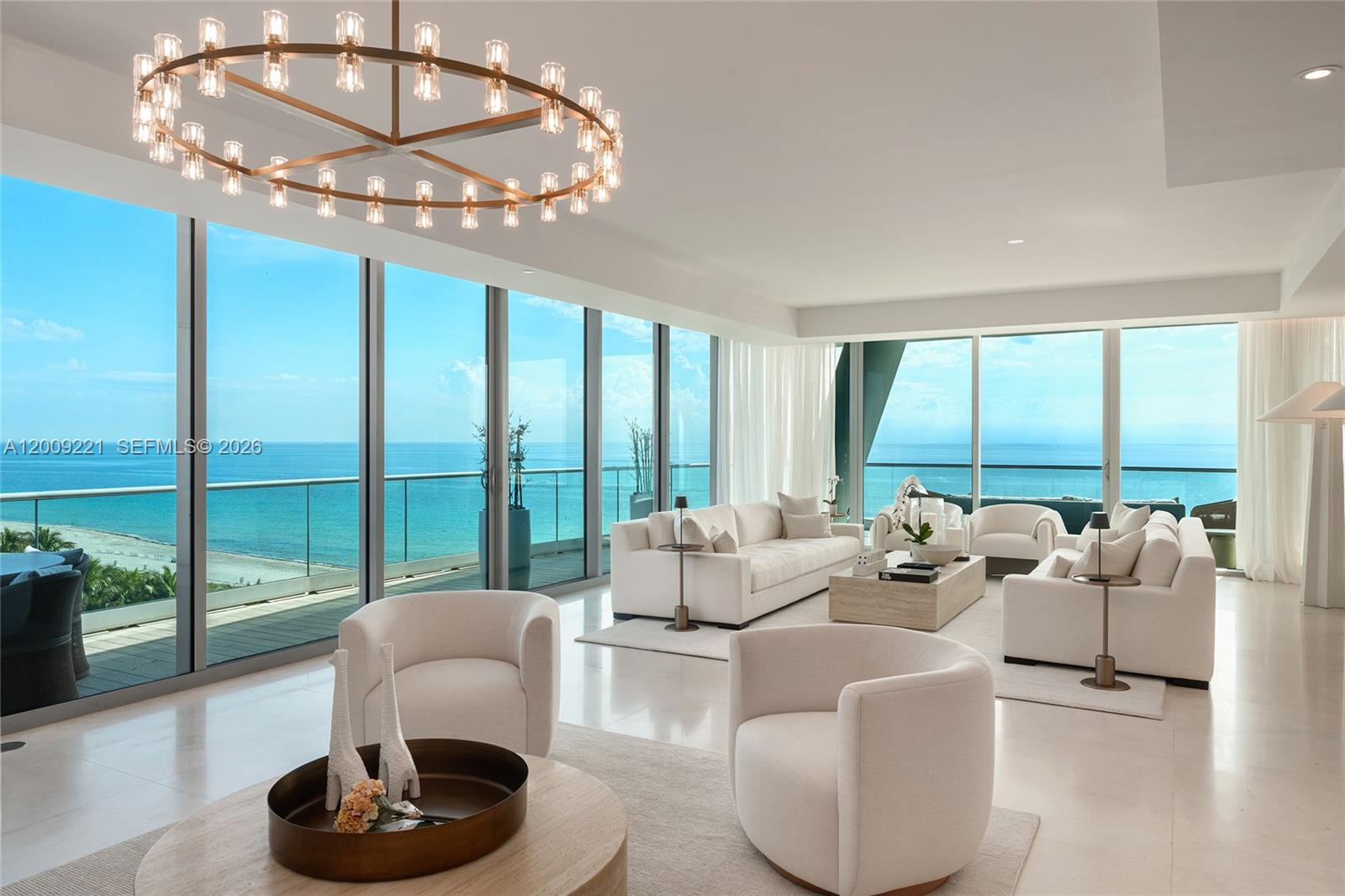 A bright living room features white furniture, a circular chandelier, and floor-to-ceiling ocean views — 9349 Collins Ave # 801, Surfside FL 33154, SURFSIDE, FL