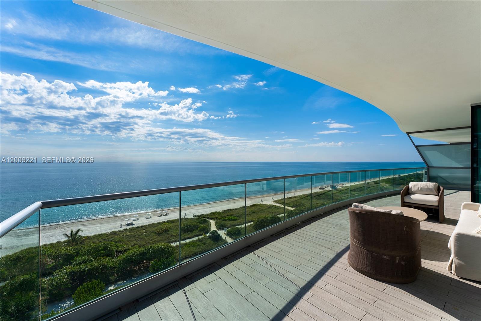 A curved balcony with glass railings overlooks a beach and the ocean — 9349 Collins Ave # 801, Surfside FL 33154, SURFSIDE, FL