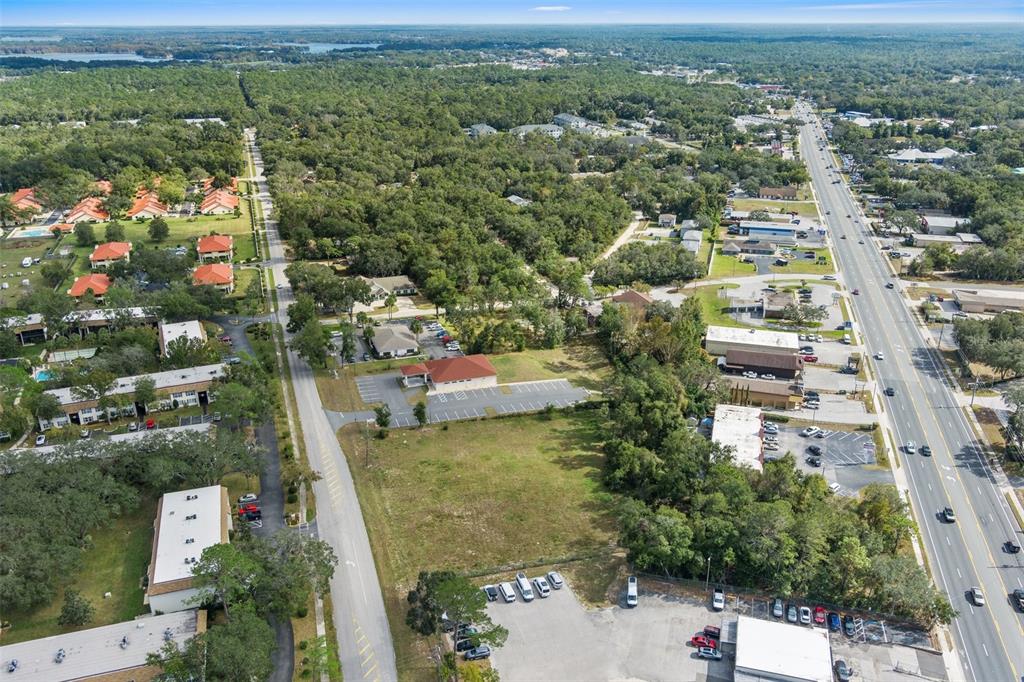 An aerial view shows a commercial building with a parking lot surrounded by trees and roads — 2514 HIGHWAY 44 W, INVERNESS, FL