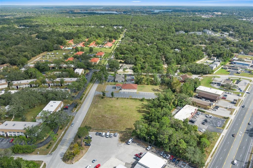 An aerial view shows a vacant lot situated between a road and a commercial building — 2514 HIGHWAY 44 W, INVERNESS, FL