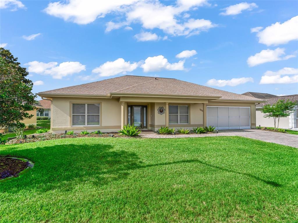 A single-story house with a tan stucco exterior, a hip roof, and a two-car garage — 11086 SE 175TH PLACE, SUMMERFIELD, FL