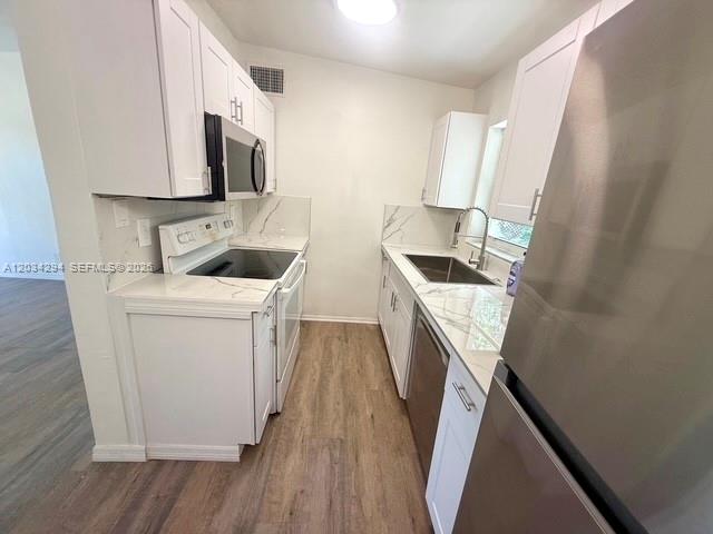 A galley kitchen features white cabinets, stainless steel appliances, and marble-patterned countertops — 530 Mentone Rd, Lake Worth FL 33462, LAKE WORTH, FL