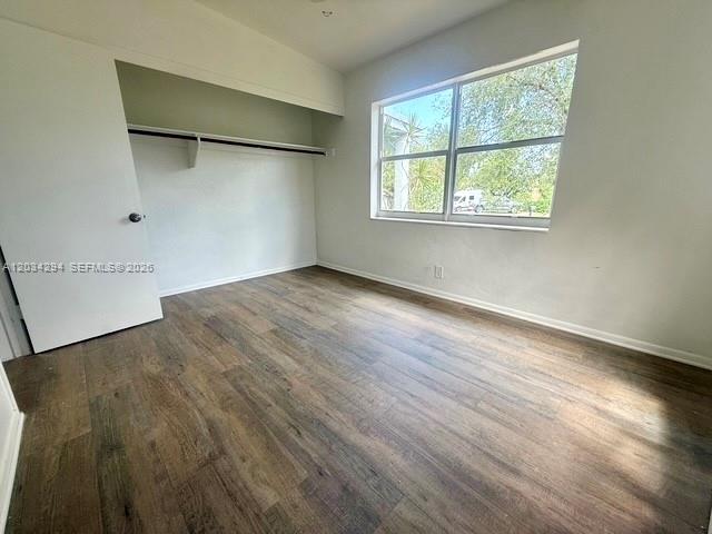 An empty bedroom features wood-look flooring, a white closet door, and a large window — 530 Mentone Rd, Lake Worth FL 33462, LAKE WORTH, FL