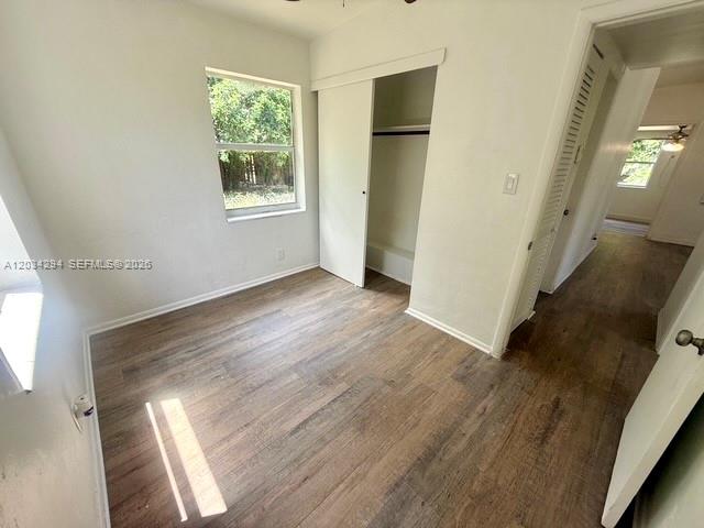 An empty bedroom features wood-look flooring, a window, and a sliding closet door — 530 Mentone Rd, Lake Worth FL 33462, LAKE WORTH, FL