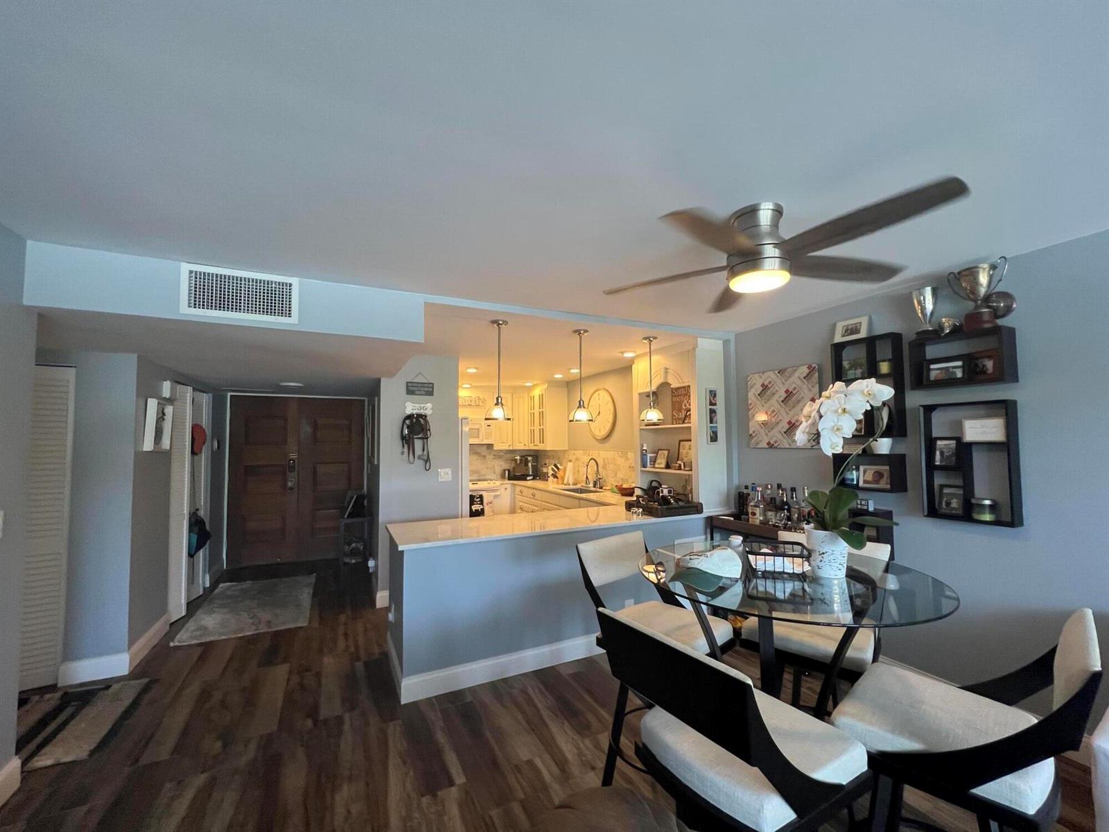 A dining area with a glass table and chairs opens to a kitchen with bar seating — 2175 S Ocean Boulevard # 103, Delray Beach FL 33483, DELRAY BEACH, FL