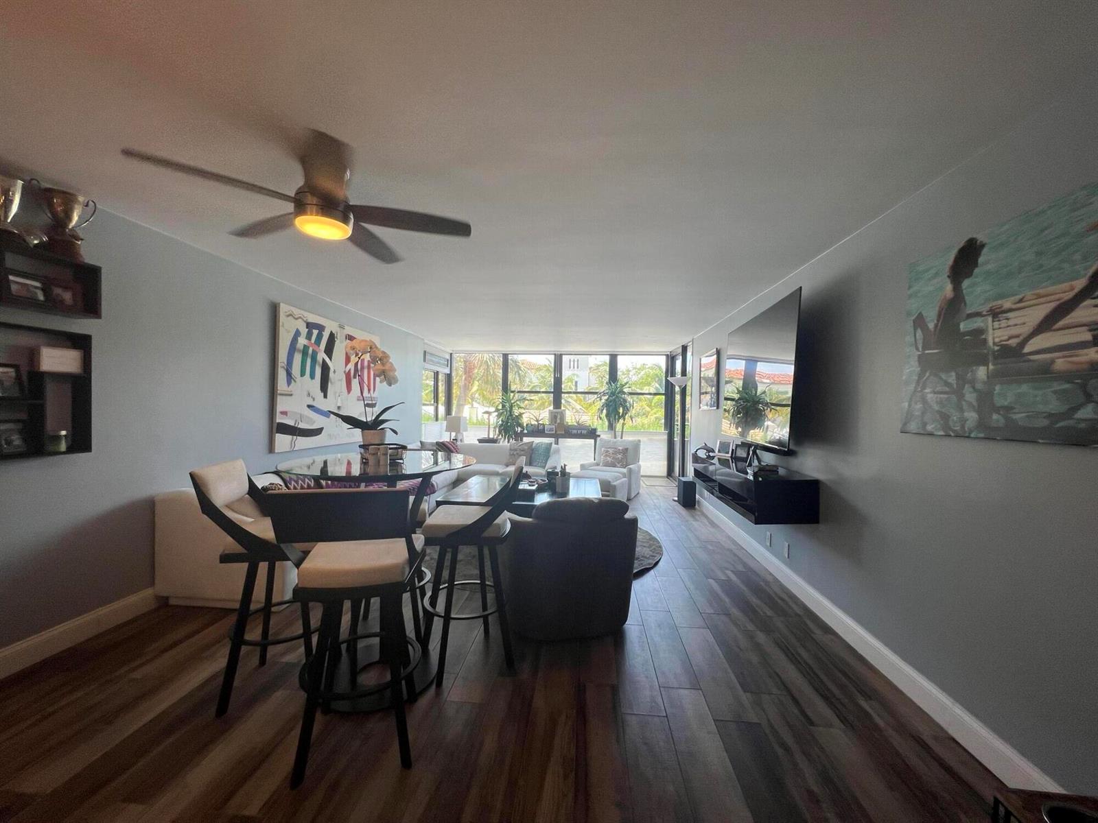 A living and dining area features wood-look tile flooring, a ceiling fan, and large windows — 2175 S Ocean Boulevard # 103, Delray Beach FL 33483, DELRAY BEACH, FL