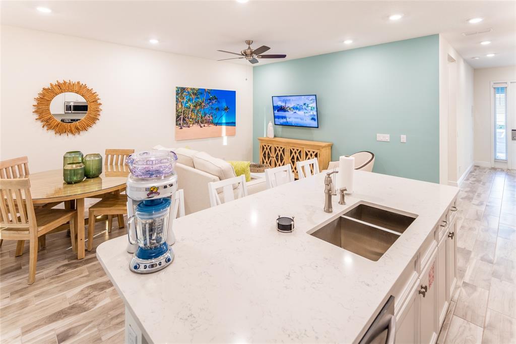 A kitchen island with a sink and blender overlooks an open-concept living and dining area — 2924 CARIBBEAN SOUL DRIVE, KISSIMMEE, FL