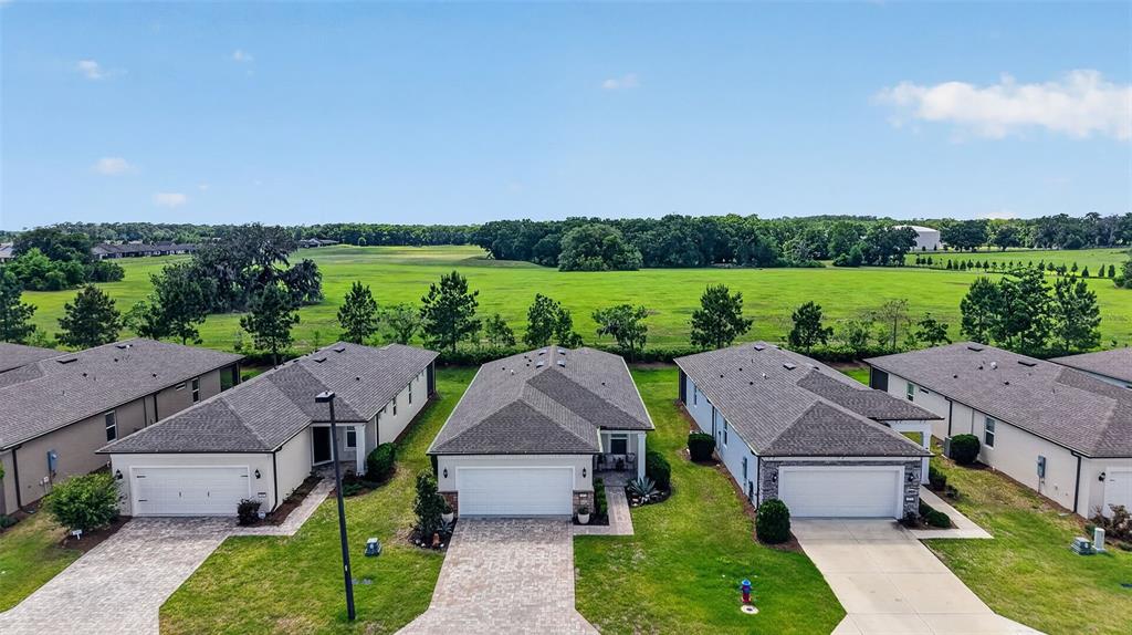 An aerial view shows a row of suburban houses with paved driveways facing a field — 6042 SW 93RD CIRCLE, OCALA, FL