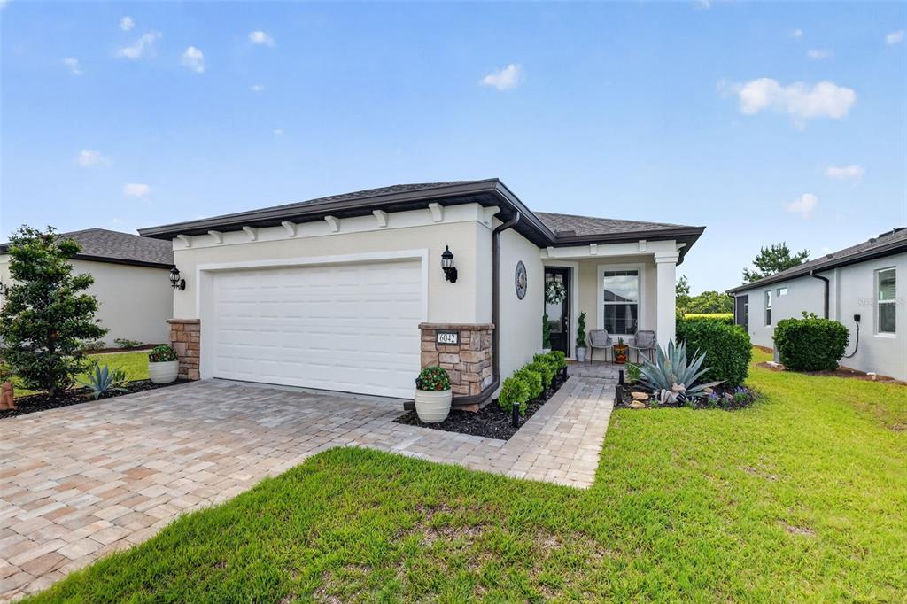 A single-story house with a white garage, stone accents, and a paved walkway — 6042 SW 93RD CIRCLE, OCALA, FL