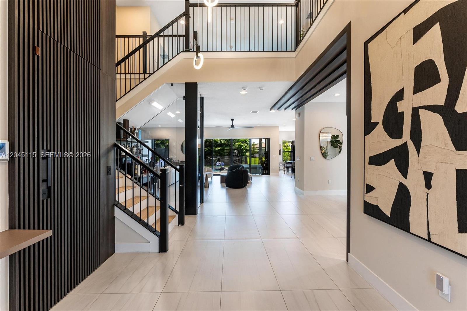 A modern entryway features a staircase with black railings, tile flooring, and abstract wall art — 8524 Shoreacres St, Boca Raton FL 33434, BOCA RATON, FL