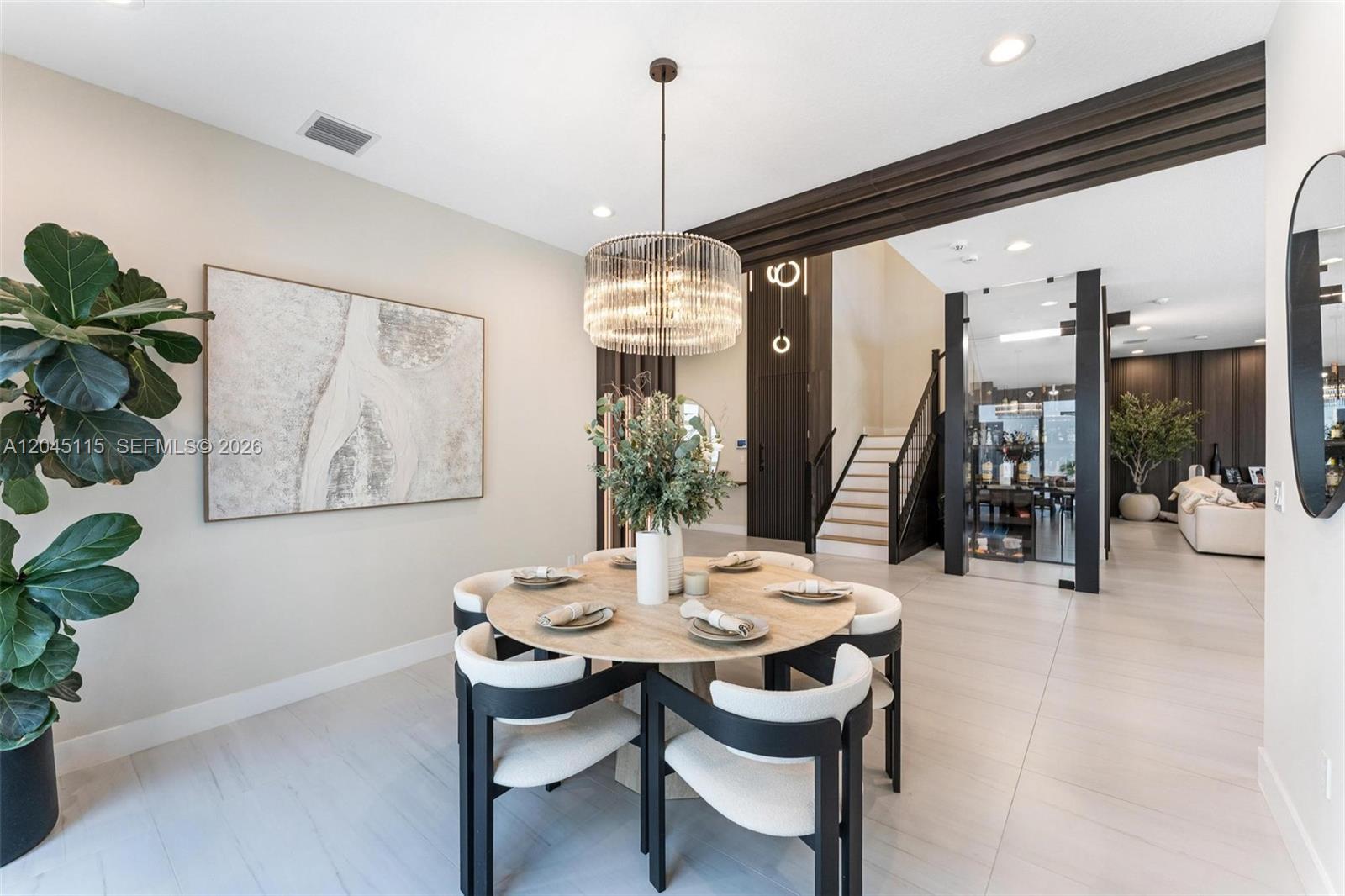 A dining area features a round wooden table, modern chairs, and a crystal chandelier — 8524 Shoreacres St, Boca Raton FL 33434, BOCA RATON, FL