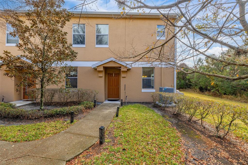 The exterior of a two-story tan townhouse features a brown front door and a concrete walkway — 1532 SCARLET OAK LOOP UNIT 70B, WINTER GARDEN, FL