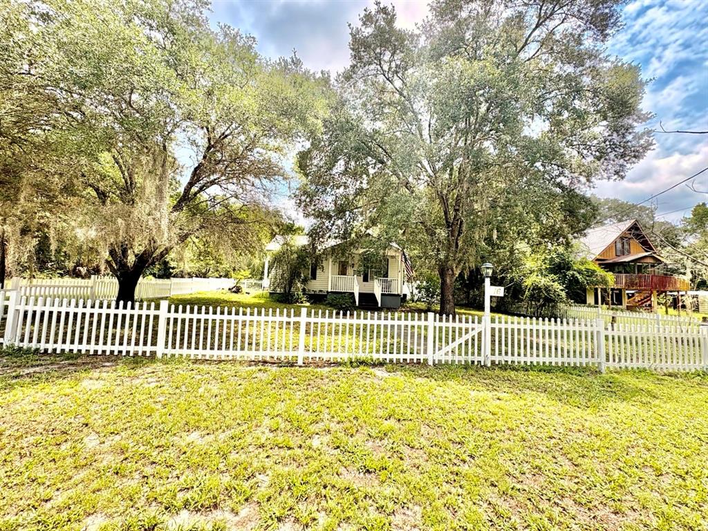 A white picket fence surrounds a yard with mature trees in front of a house — 16 52ND STREET, YANKEETOWN, FL