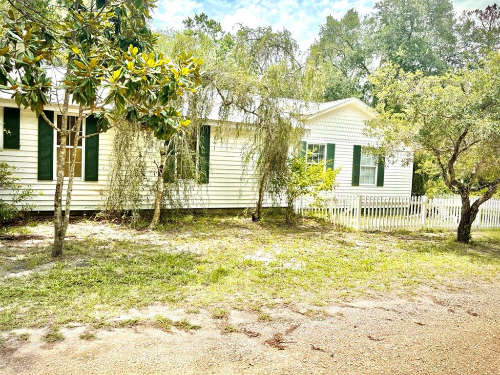 A white single-story house with green shutters sits behind a white picket fence — 16 52ND STREET, YANKEETOWN, FL
