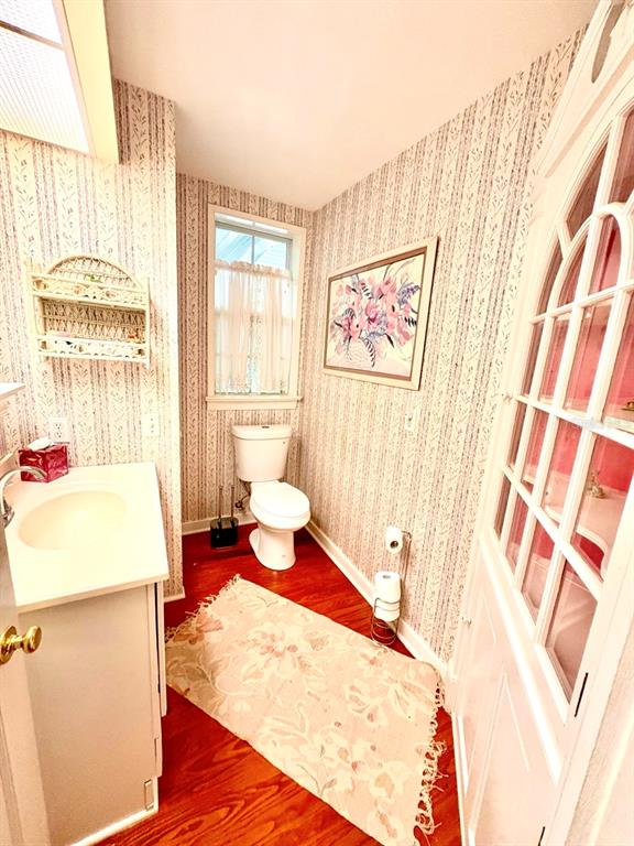 A bathroom features floral wallpaper, a white vanity, a toilet, and a wood-look floor — 16 52ND STREET, YANKEETOWN, FL