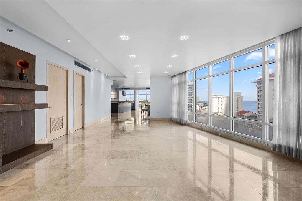 A spacious living area features polished tile floors, recessed lighting, and floor-to-ceiling windows with ocean views — 1052 ASHFORD AVENUE UNIT 9C, SAN JUAN, PR