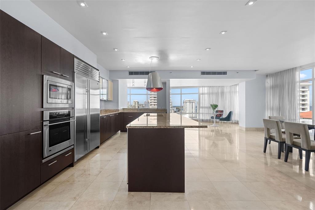 A modern kitchen features dark wood cabinetry, stainless steel appliances, and a large granite island — 1052 ASHFORD AVENUE UNIT 9C, SAN JUAN, PR