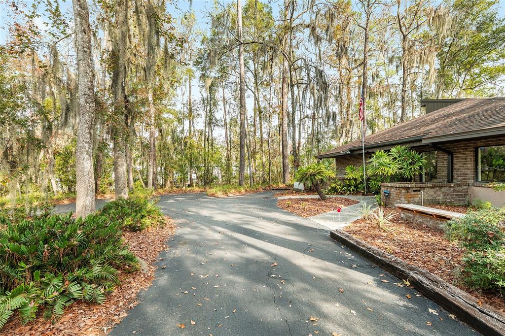 A paved driveway leads toward a brick building surrounded by trees with Spanish moss — 2750 SE 17TH STREET, OCALA, FL