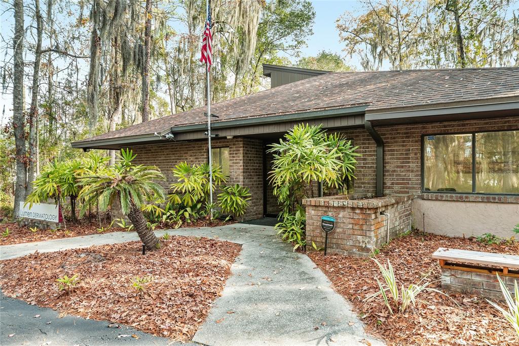 A brick medical office building features a concrete walkway, landscaping, and an American flag — 2750 SE 17TH STREET, OCALA, FL