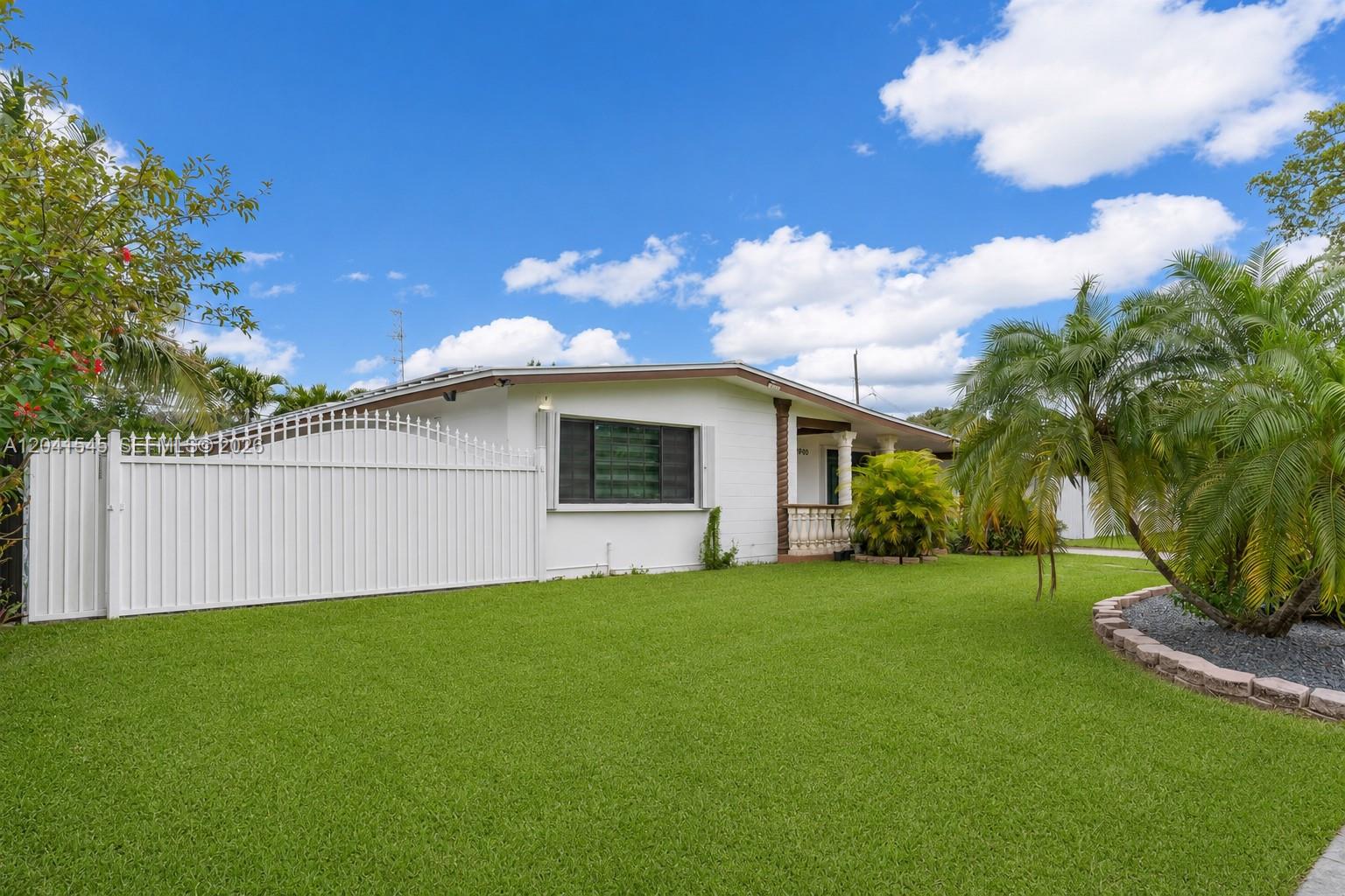 A white single-story house features a fenced yard, green lawn, and a palm tree — 18670 Belview Dr, Cutler Bay FL 33157, CUTLER BAY, FL