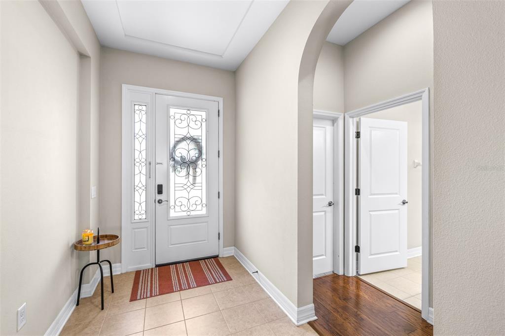 A tiled entryway leads to a front door with a decorative glass insert and a bathroom — 2397 GWYNHURST BOULEVARD, WESLEY CHAPEL, FL