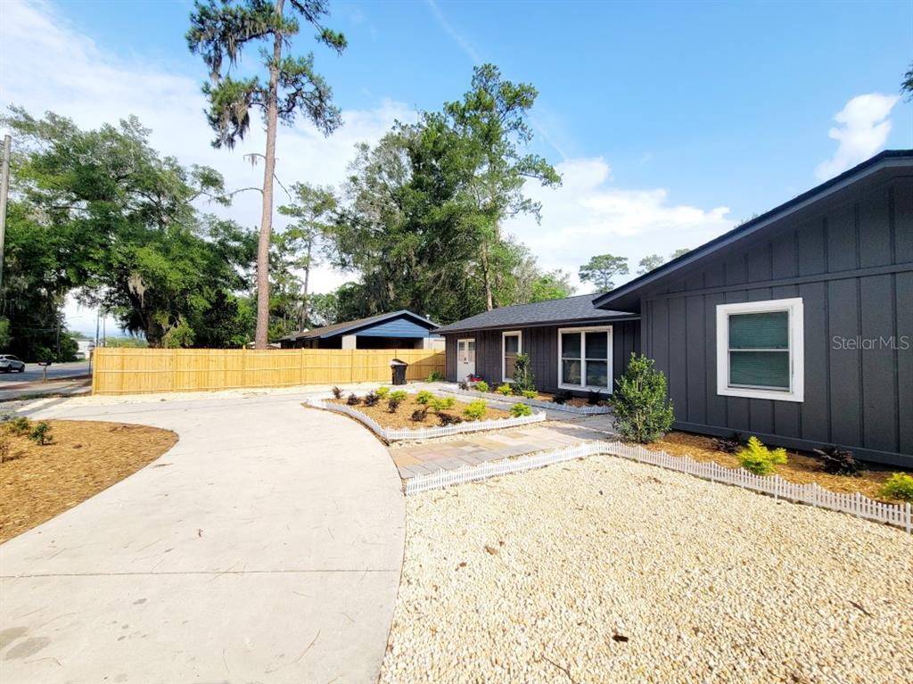 A gray house with a concrete driveway, gravel landscaping, and a wooden fence — 3116 W UNIVERSITY AVENUE, GAINESVILLE, FL