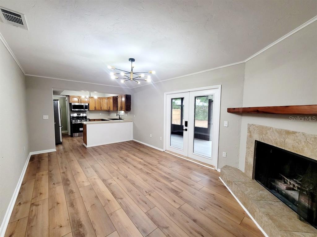 A living room with wood-look flooring, a fireplace, and an open kitchen with wood cabinets — 3116 W UNIVERSITY AVENUE, GAINESVILLE, FL
