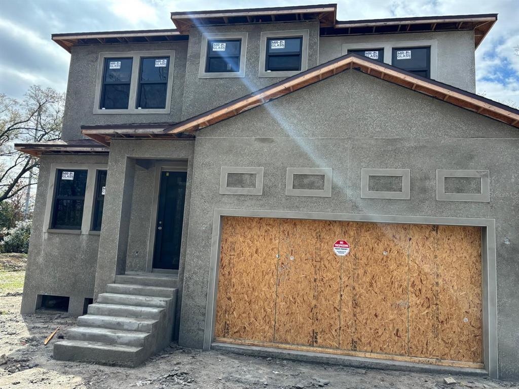 An exterior view of a two-story house under construction with stucco siding and boarded windows — 2120 W BIRD ST., TAMPA, FL