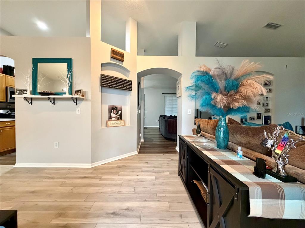 A view of a living area with light wood flooring, an arched entryway, and decor — 4303 ORANGE RIDGE COURT, VALRICO, FL