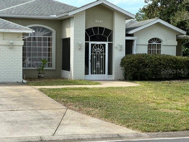 A single-story house with a white brick facade, arched windows, and a central entryway — 9685 SOUTHERN BELLE DRIVE, WEEKI WACHEE, FL