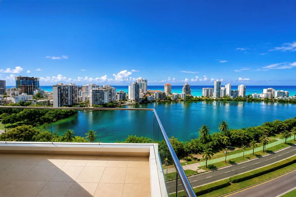 A balcony with a glass railing overlooks a lake, a road, and a city skyline — 555 MONSERRATE, SAN JUAN, PR