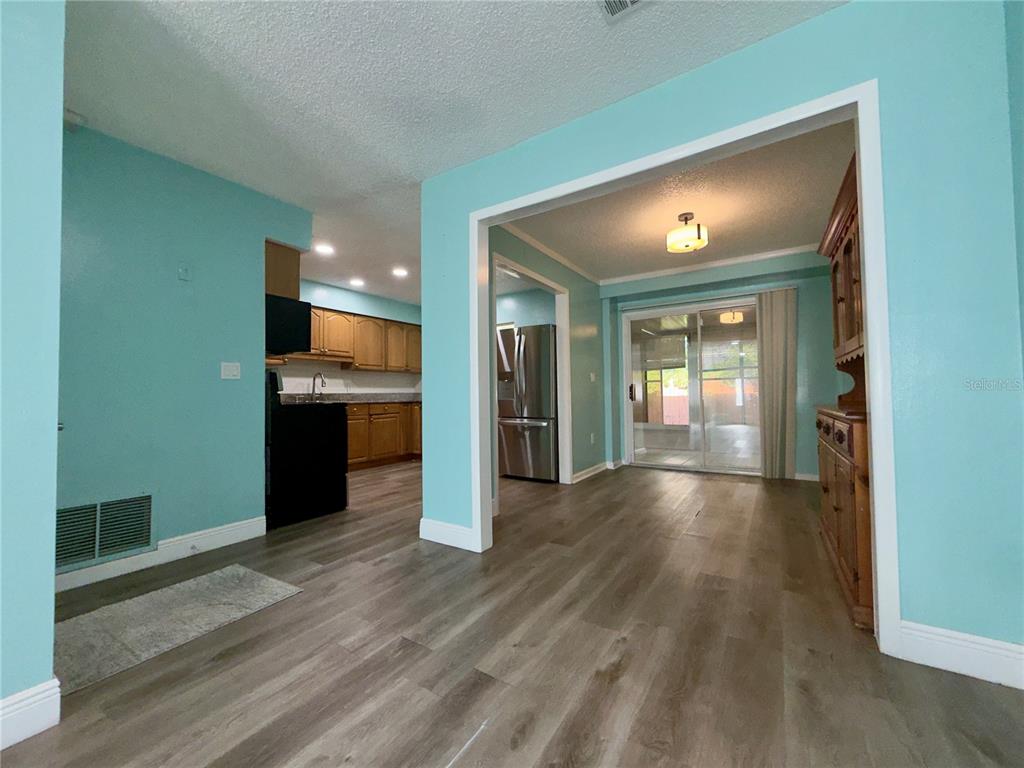 A kitchen with wood cabinets and a dining area featuring light wood-look flooring — 9805 LILY STREET N UNIT 9805, PINELLAS PARK, FL