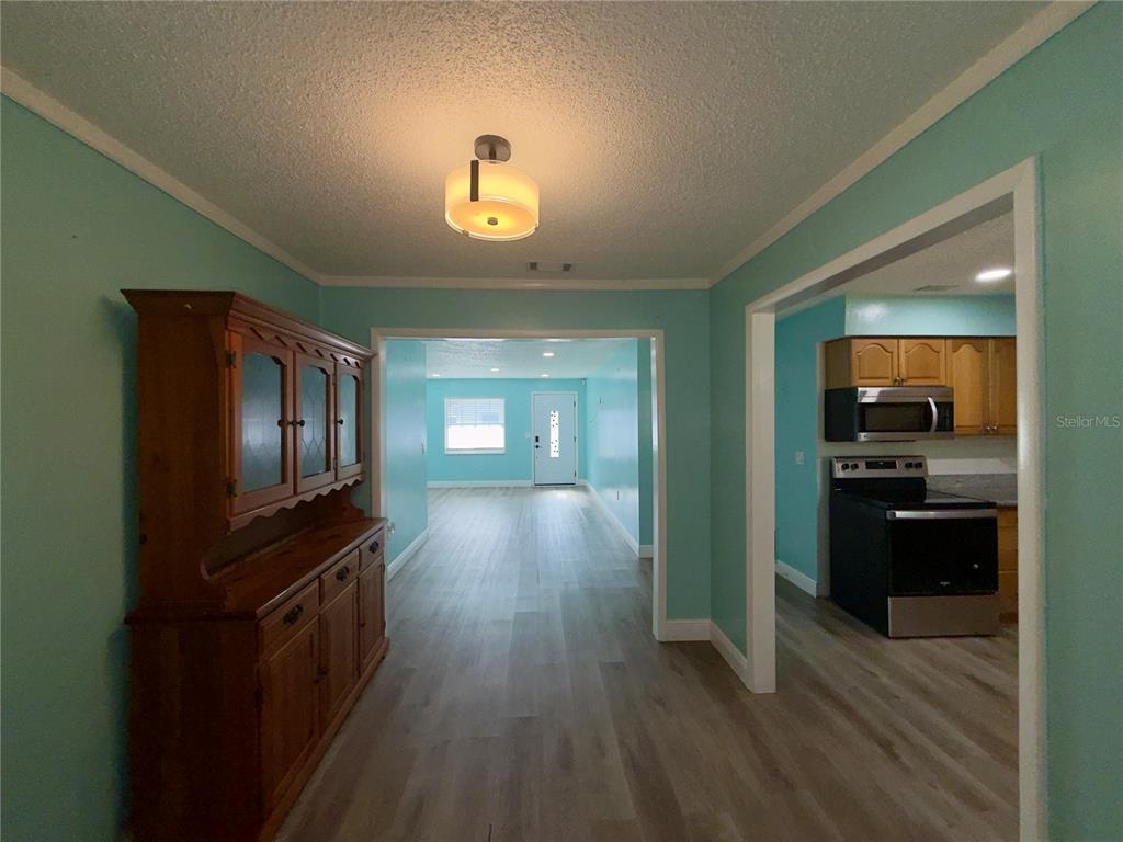 A dining area with a wooden hutch leads to a kitchen and a living room — 9805 LILY STREET N UNIT 9805, PINELLAS PARK, FL