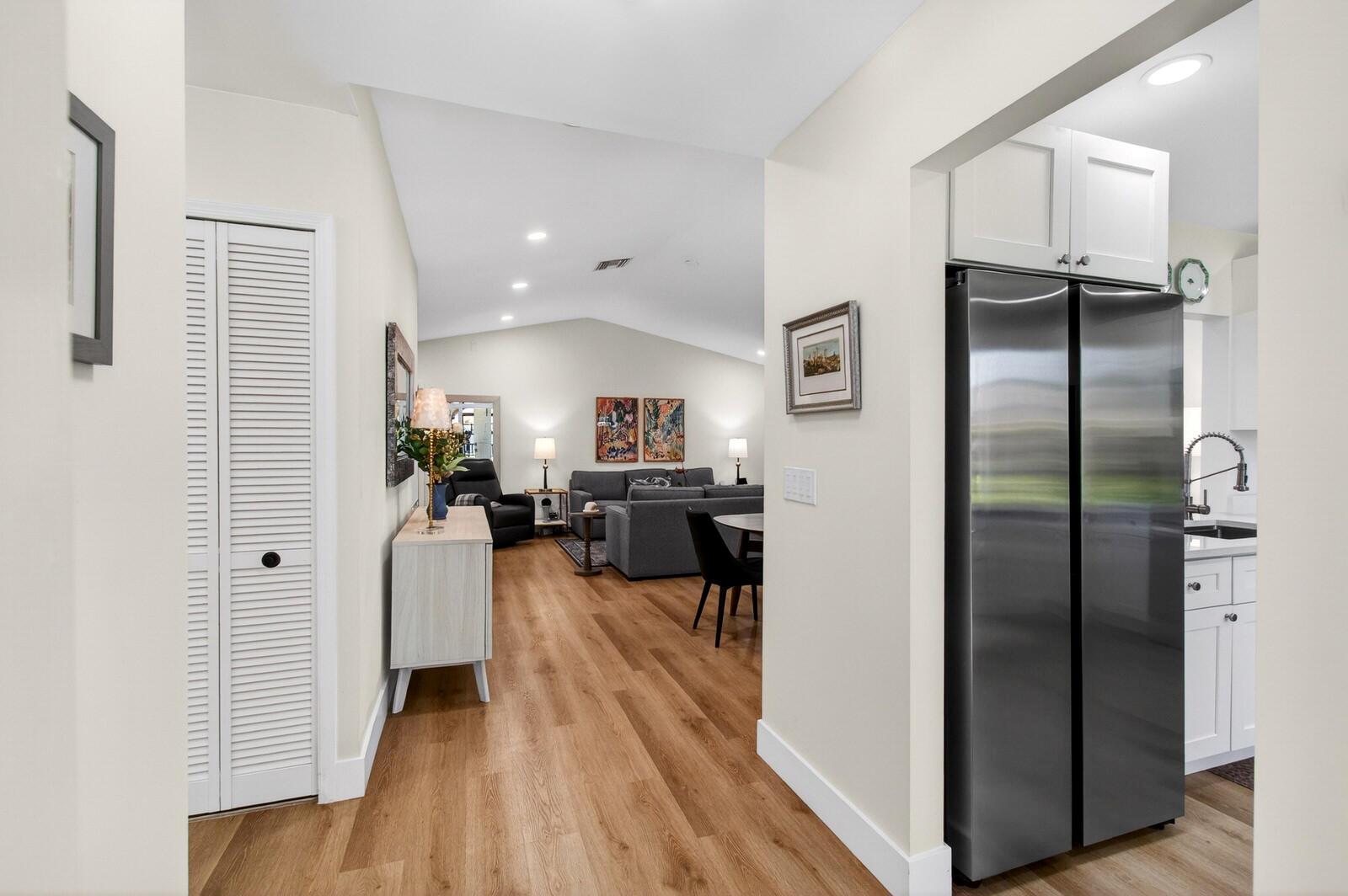 A hallway leads into an open-concept living area with light wood flooring and stainless appliances — 23377 Barlake Drive, Boca Raton FL 33433, BOCA RATON, FL