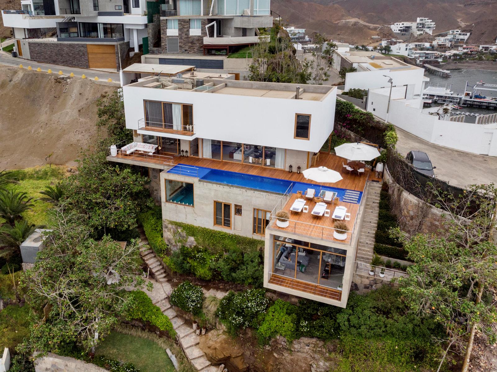 An aerial view of a modern multi-level house with a pool, wooden deck, and landscaping — 0600 Zona Sol Del Mar Mz.J Lt.5-6 # 0026, FL