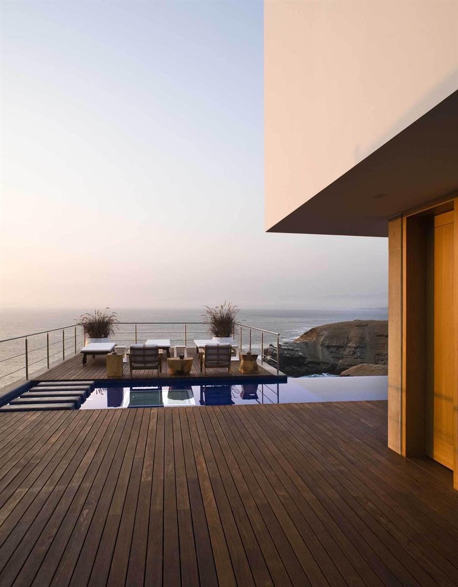 A wooden deck with lounge chairs overlooks a swimming pool and the ocean at sunset — 0600 Zona Sol Del Mar Mz.J Lt.5-6 # 0026, FL