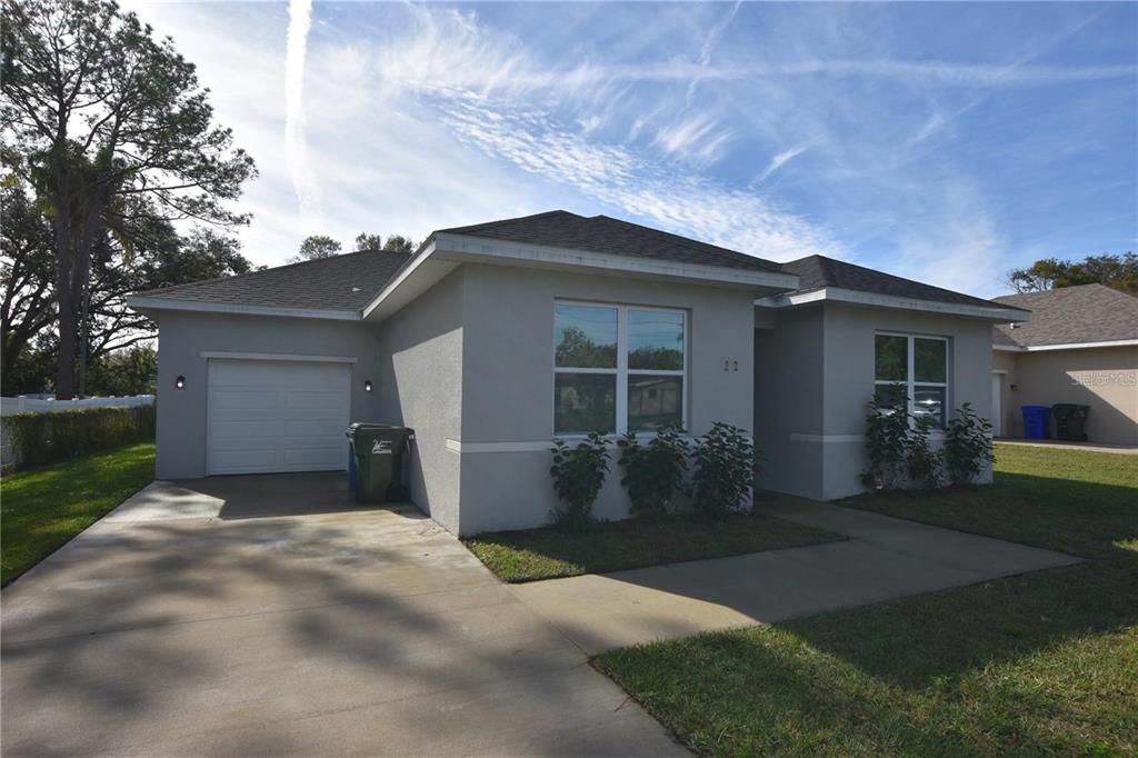 A single-story house with a gray stucco exterior, a one-car garage, and a concrete driveway — 202 W CRESCENT DRIVE, LAKELAND, FL