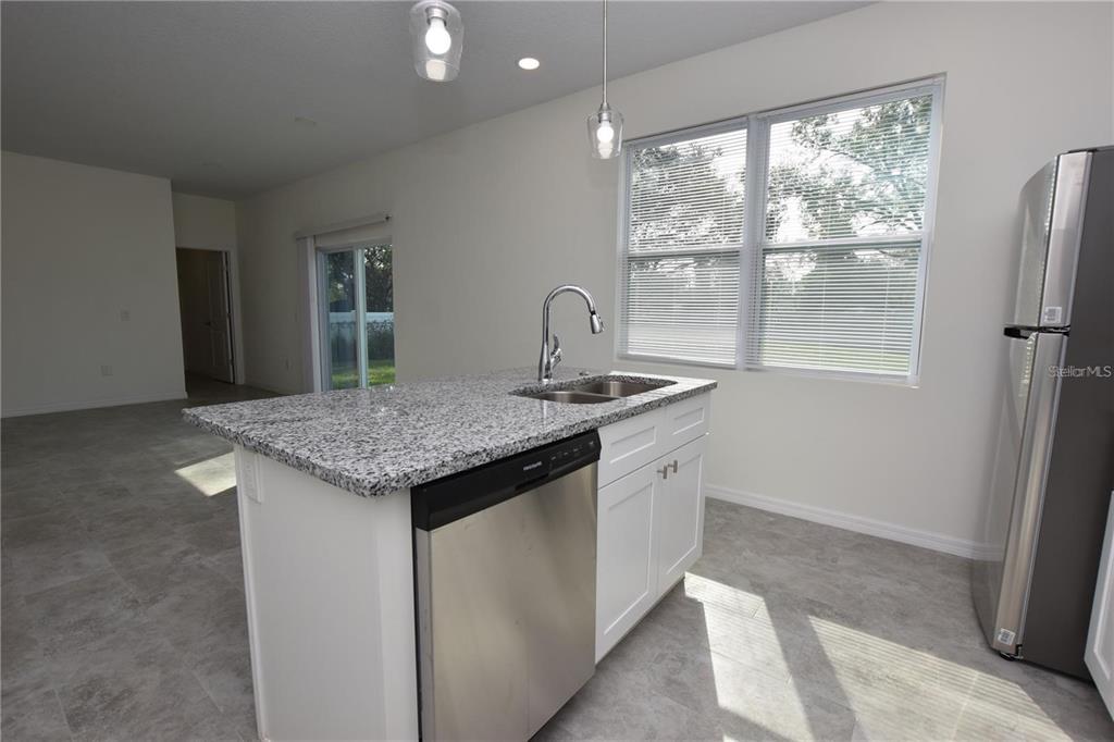 A kitchen island with a stainless steel dishwasher and granite countertop sits in a room — 202 W CRESCENT DRIVE, LAKELAND, FL