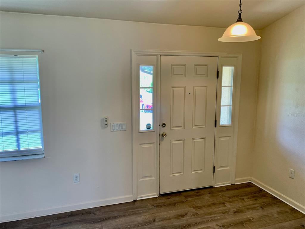 An entryway features a white front door with sidelights, a window, and wood-look flooring — 8310 DELK AVENUE, NORTH PORT, FL