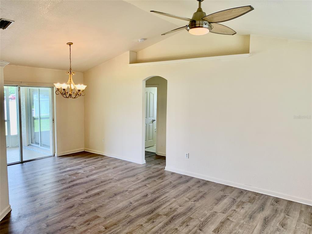 An open living area features wood-look flooring, a ceiling fan, and a sliding glass door — 8310 DELK AVENUE, NORTH PORT, FL