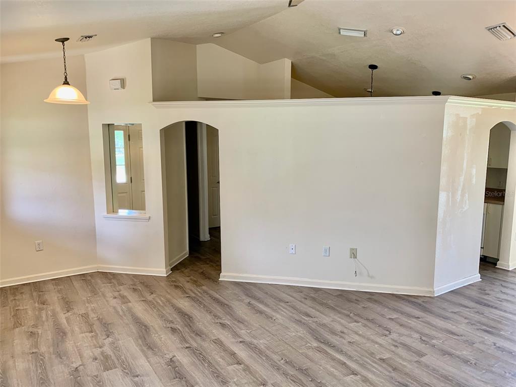 A living area features light wood-look flooring, a vaulted ceiling, and a central arched doorway — 8310 DELK AVENUE, NORTH PORT, FL