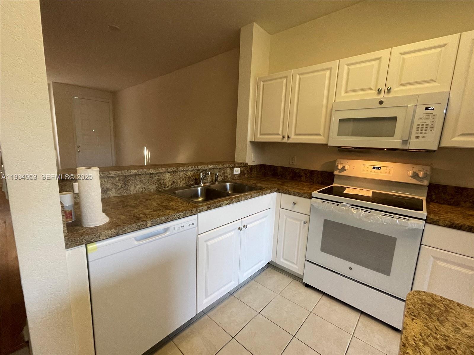 A kitchen features white cabinetry, a white stove, a dishwasher, and brown laminate countertops — 3550 Oleander Ter, Riviera Beach FL 33404, RIVIERA BEACH, FL