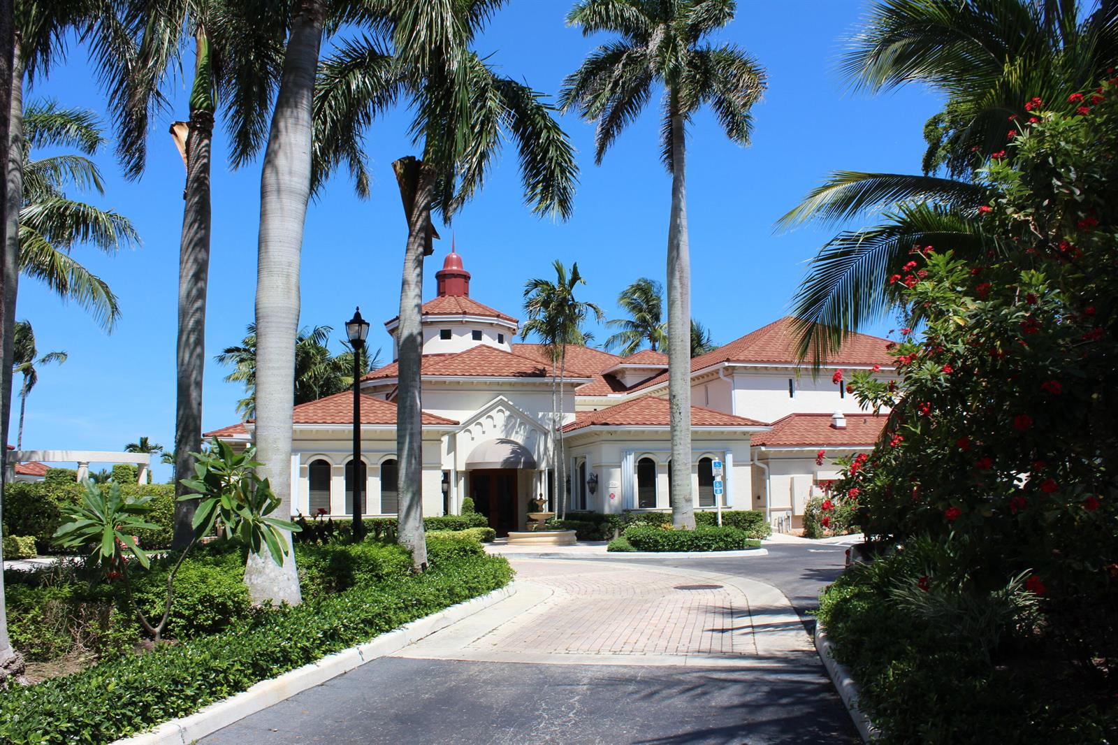 A paved driveway leads to the entrance of a Mediterranean-style building with palm trees — 3302 Tuscany Way, Boynton Beach FL 33435, BOYNTON BEACH, FL