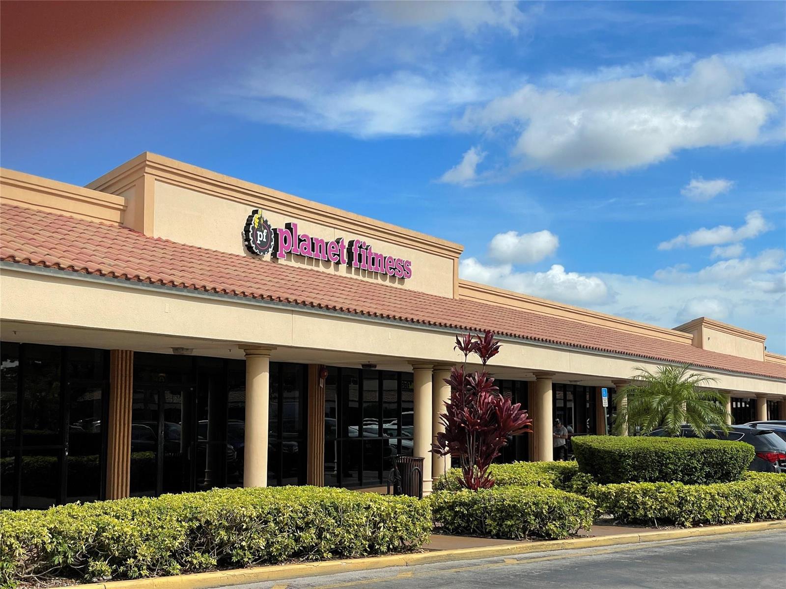A Planet Fitness gym storefront features a tan facade, tile roof, and manicured landscaping — 18606 NW 67th Avenue, Hialeah FL 33015, HIALEAH, FL