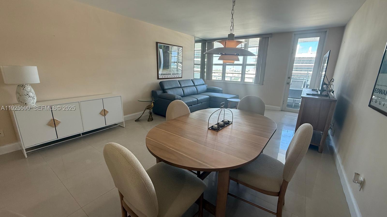 A dining area with a wooden table and chairs sits in front of a living space — 100 Lincoln Rd # 1108, Miami Beach FL 33139, MIAMI BEACH, FL